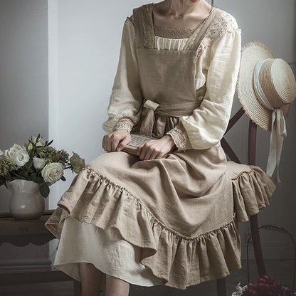 Woman seated wearing the garden apron with a straw hat resting beside her