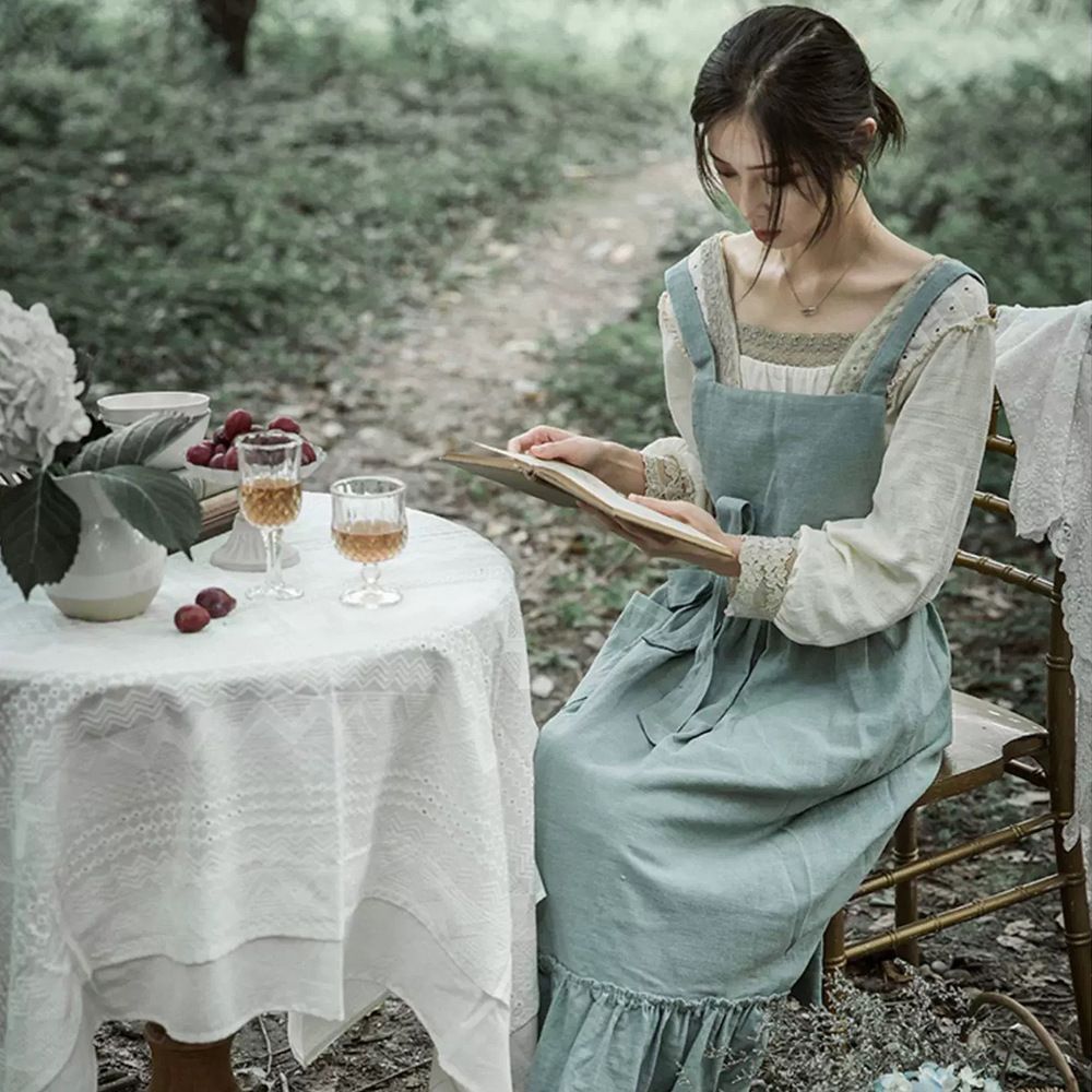 Woman reading at an outdoor table wearing the garden apron