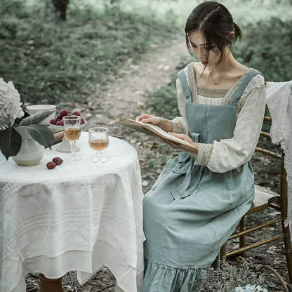 Woman reading at an outdoor table wearing the garden apron