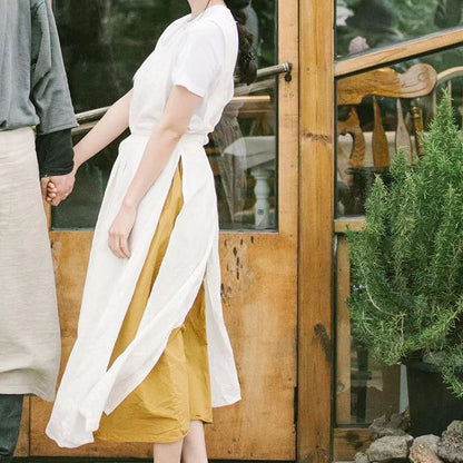 Woman wearing the garden apron over a yellow skirt beside a greenhouse door