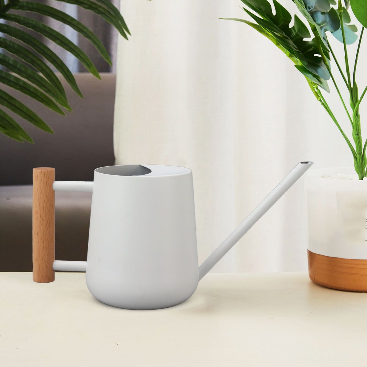 White watering can styled on a table with indoor plants