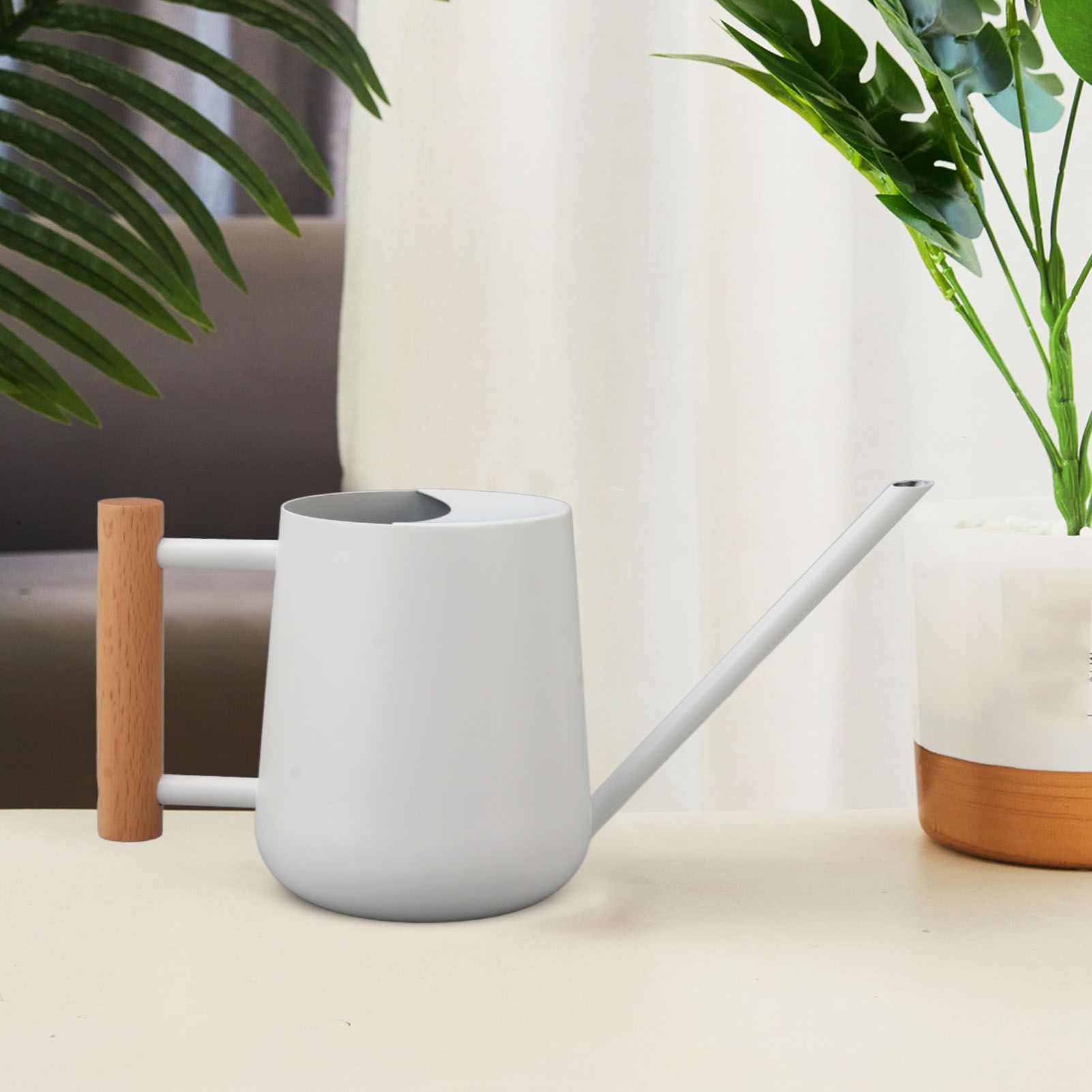 White watering can styled on a table with indoor plants