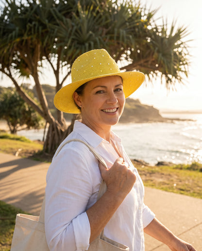 Woman walking near the coast wearing the yellow straw hat